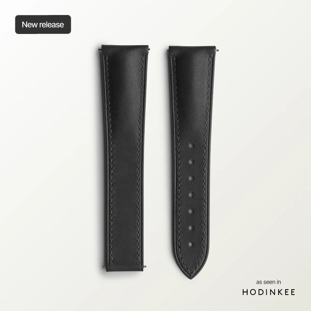 Black leather watch strap on a light gray background.