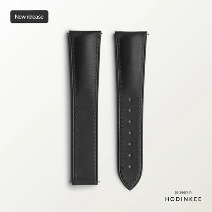 Black leather watch strap on a light gray background.